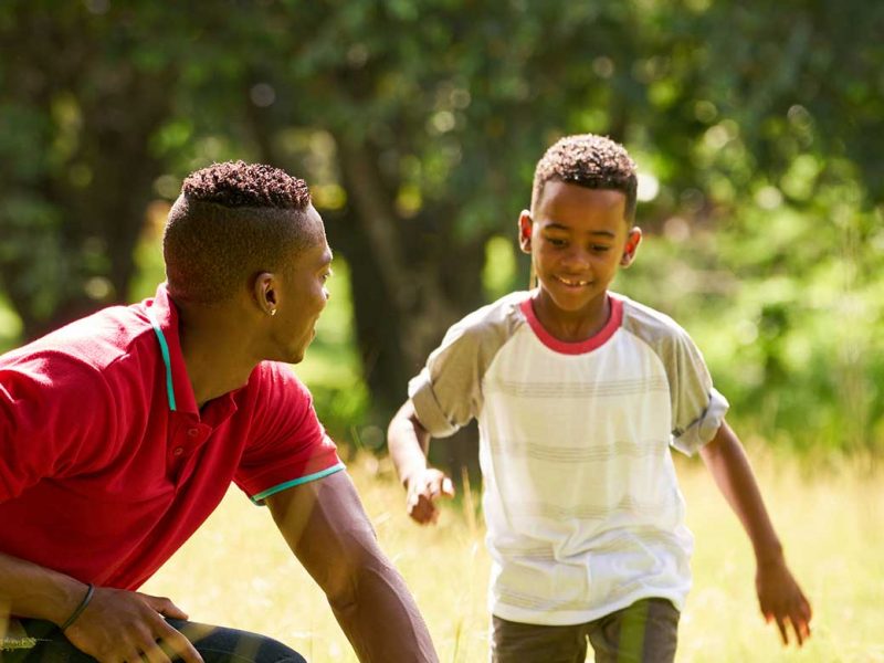 African Amercian Father and Son playing in field