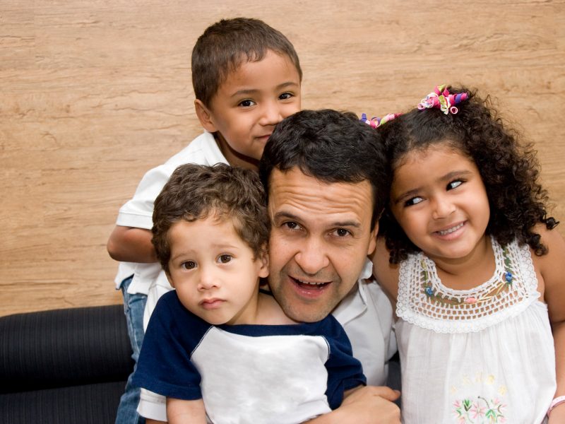 Ethnic father with 2 sons and a daughter gathered around him