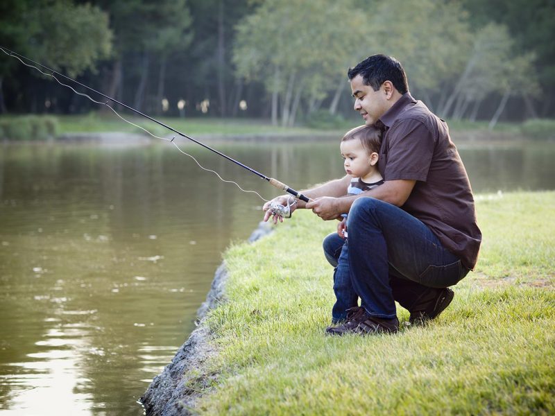 Happy Young Ethnic Father and Son Fishing in Pond